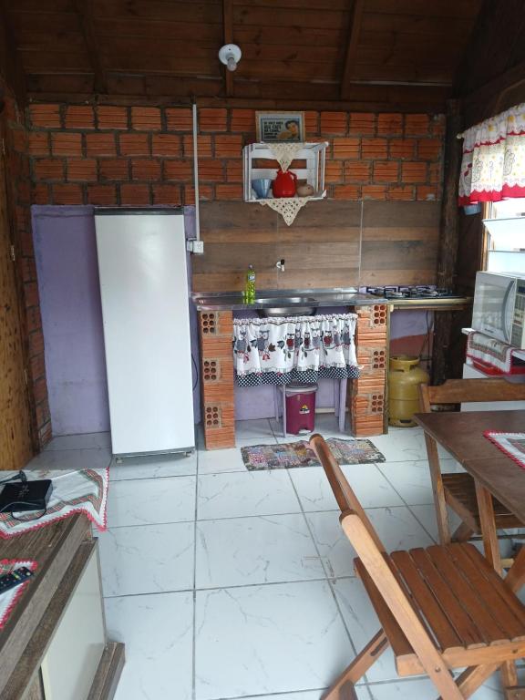 Il comprend une cuisine équipée d'un réfrigérateur, d'une table et de chaises. dans l'établissement Cabana 01, à Imbituba