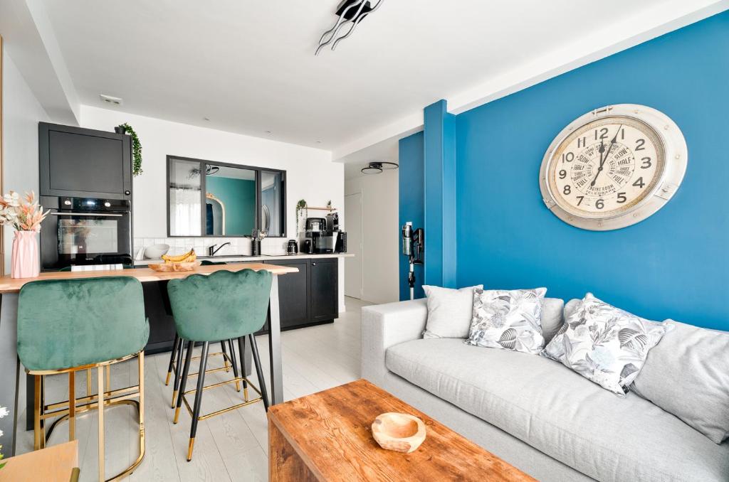 a living room with a couch and a clock on the wall at Appartement Dinard hyper centre, 2 chambres in Dinard