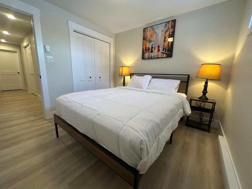 een slaapkamer met een groot wit bed met twee lampen bij Modern Private Suite in Moncton