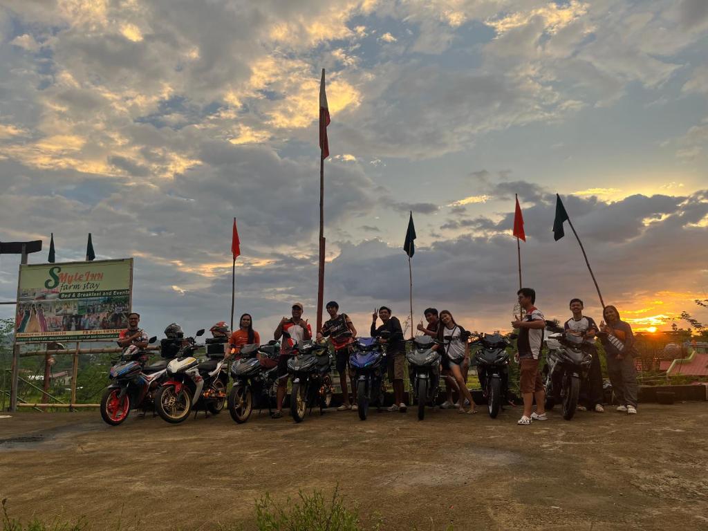 a group of people on motorcycles parked in front of flags at SMyleINN Farm in San Fernando