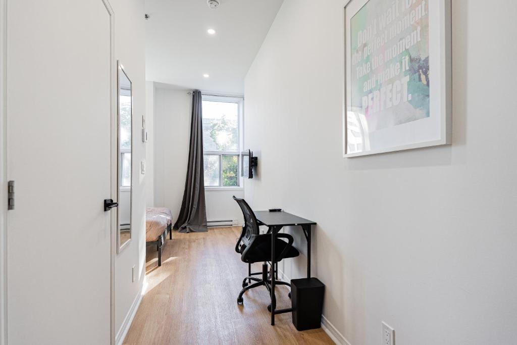 Dieses weiße Zimmer verfügt über einen Schreibtisch und ein Schlafzimmer. in der Unterkunft Studio style pour 2- Location par Semaine-Parking gratuit in Montreal