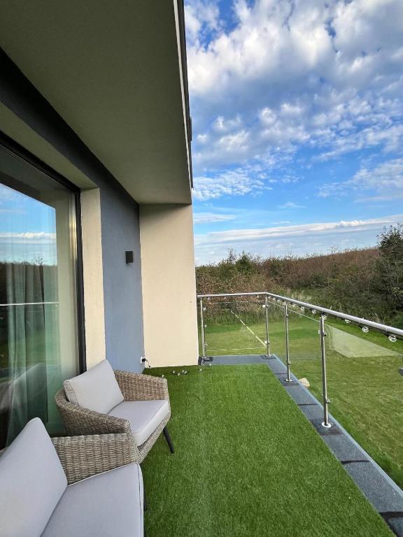 a balcony with chairs and a view of a golf course at Sadowa Ostoja z prywatnymi jacuzzi in Pierwoszyno