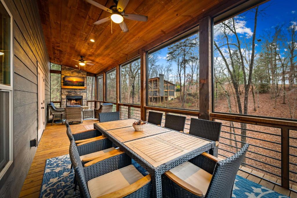 een afgeschermde veranda met een houten tafel en stoelen bij Fireside Living in Galloway