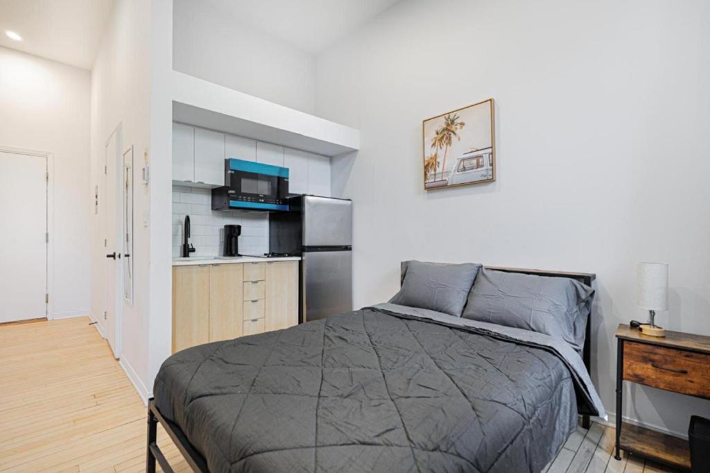 een slaapkamer met een bed en een keuken met een koelkast bij Chic Studio pour 2- 7 jours- Parking gratuit in Montreal