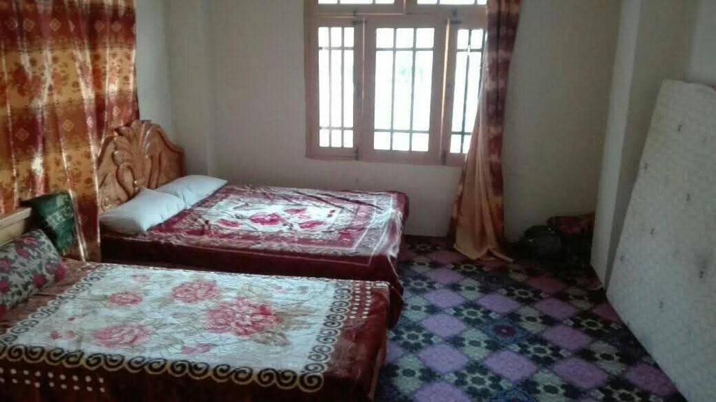 une chambre avec deux lits et une fenêtre dans l'établissement Ghani Palace Hotel Kalam, à Kārandūkai