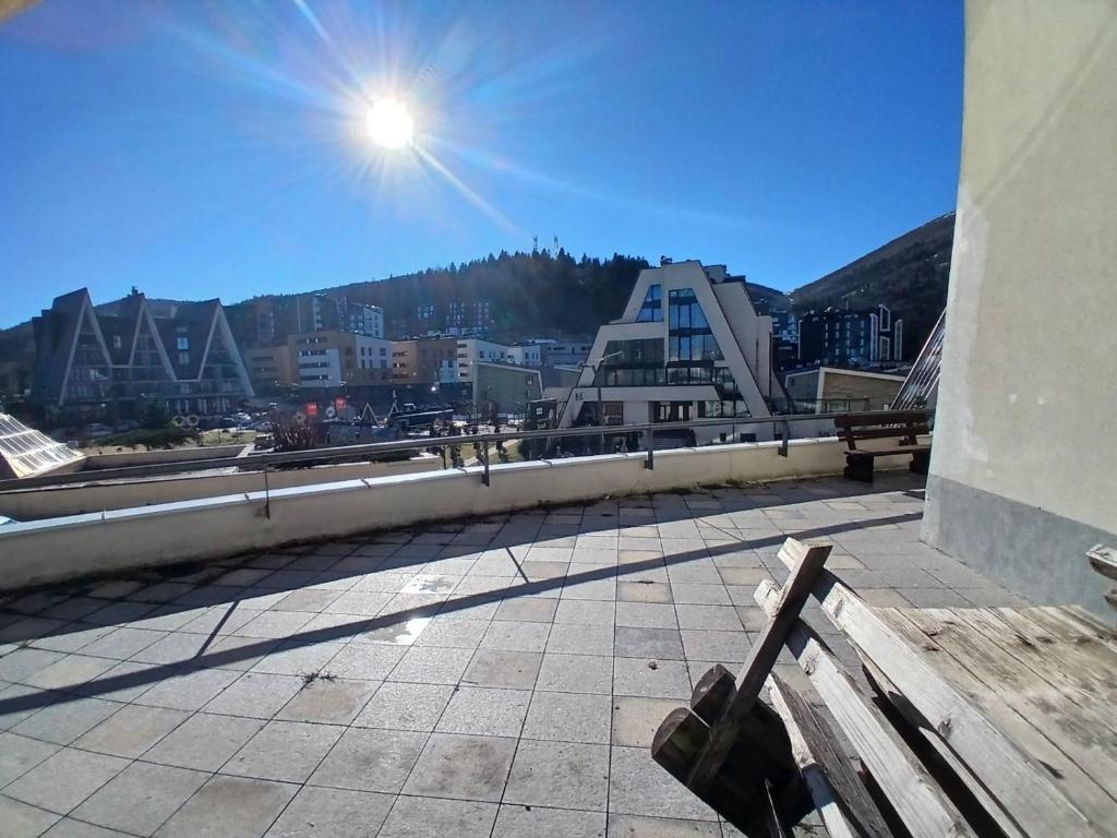 eine Bank auf einem Gebäude mit Blick auf eine Stadt in der Unterkunft Sunny Escape Bjelašnica in Ivišovo Greblje