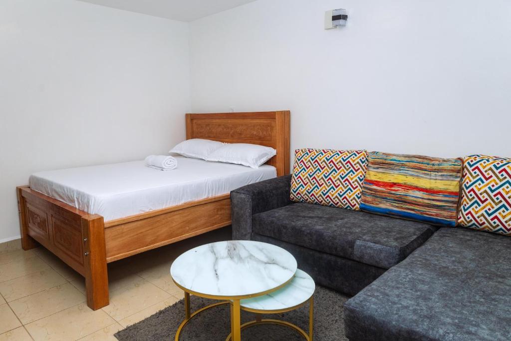 une chambre avec un lit, un canapé et une chaise dans l'établissement Kasarani Studio Apartment, à Nairobi