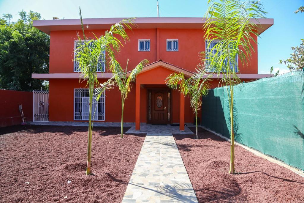 a red house with two palm trees in front of it at Casa Naranja in Ciudad Fernández