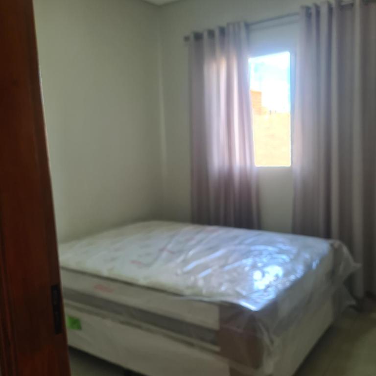 a small bedroom with a bed and a window at Montebelle casa1 in Porangaba