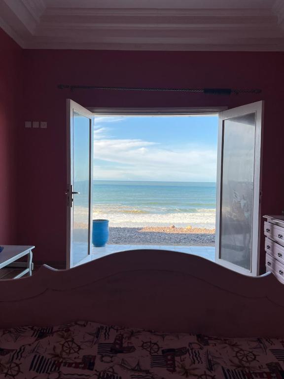 a bedroom with a large window looking out at the ocean at Beachfront villa sidi ouarzeg in Sidi Ouarsik