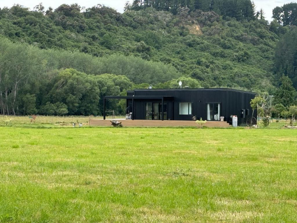una casa negra en medio de un campo en Bellbird Hideaway, en Pleasant Valley