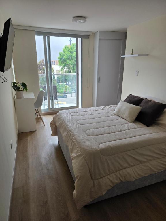 a bedroom with a large bed and a large window at Apartaestudio con vista a AV Santander Manizales in Manizales