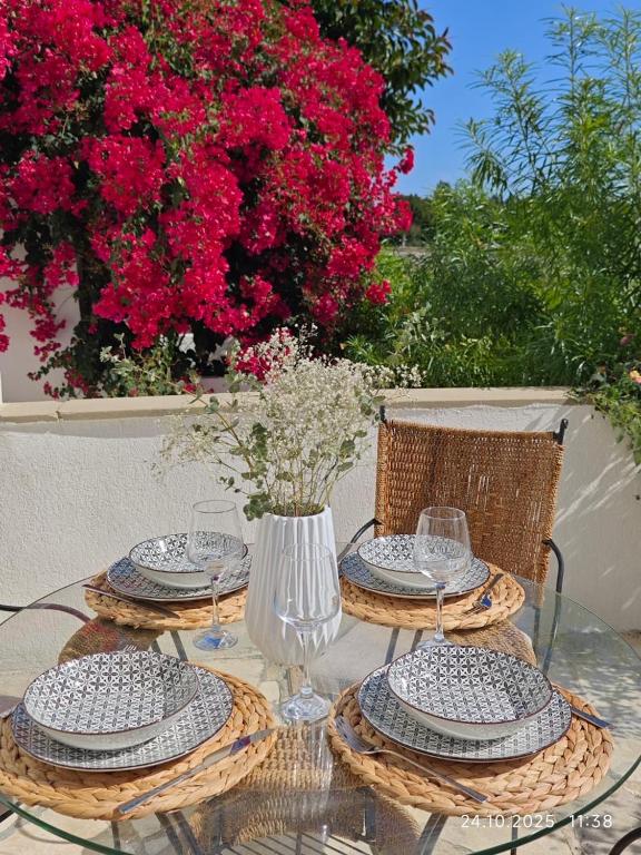 a glass table with plates and a vase with flowers at Brand New Townhouse with hotel infrastructure in Paphos