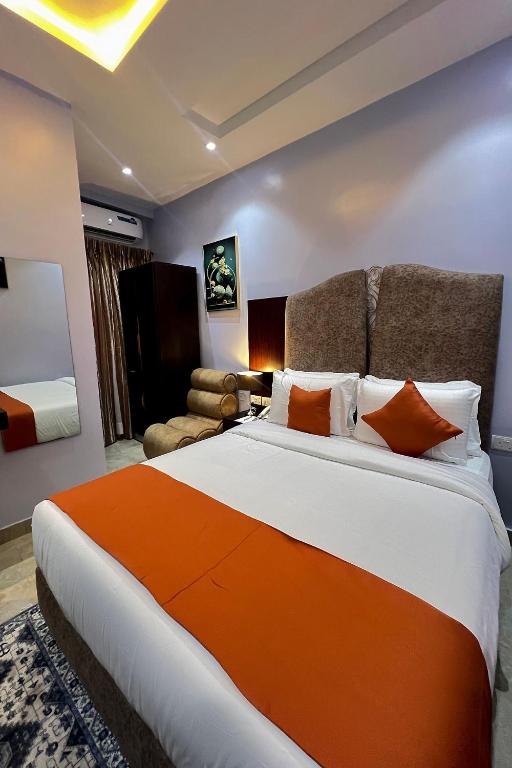 a bedroom with a large bed with an orange blanket at Kaashmeen Hotel & Suite in Lagos