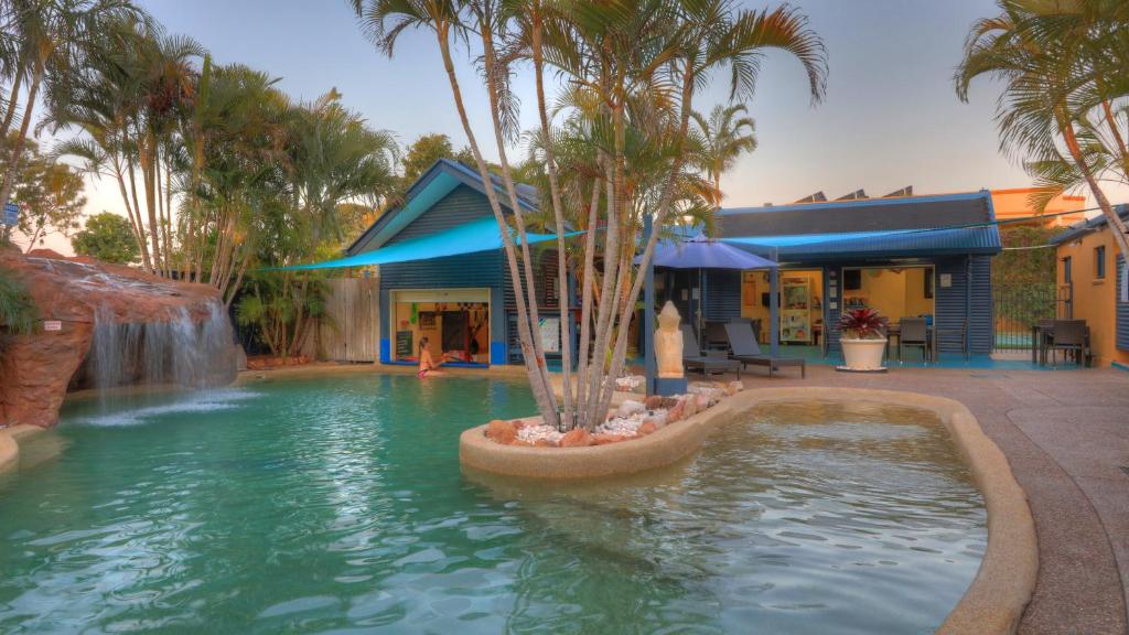 a swimming pool with a pool table, chairs, and umbrellas at Grange Resort Hervey Bay in Hervey Bay