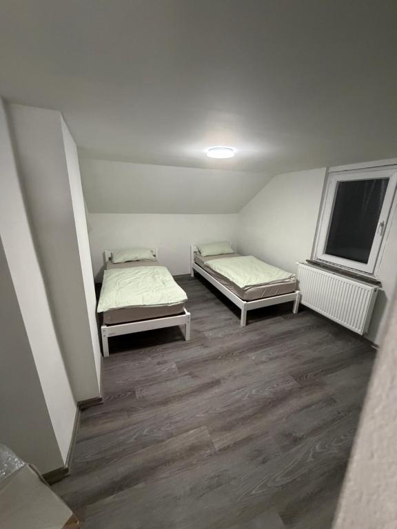 2 Betten in einem kleinen Zimmer mit Holzböden in der Unterkunft Ferienwohnung Nabo in Wadgassen