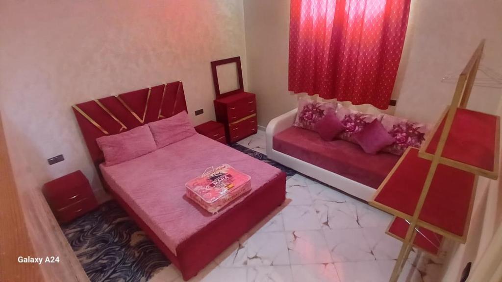 een slaapkamer met een roze bed en een bank bij شقق الراحة in Oulad Akkou