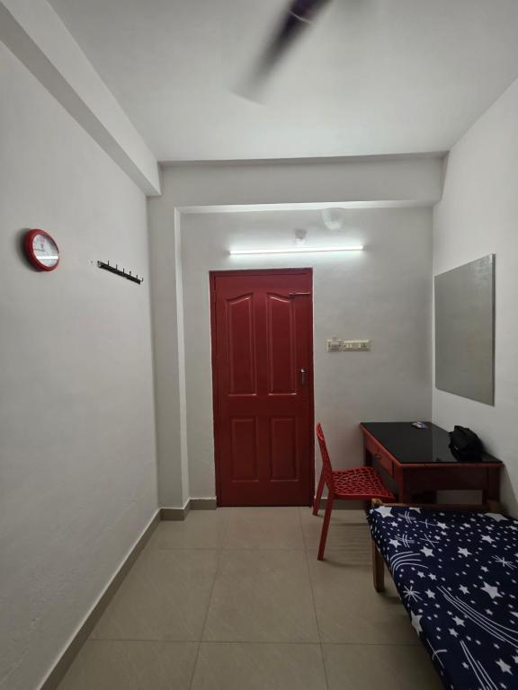 a room with a red door and a bed and a desk at FlexTays Transit - Station Side Stays in Trivandrum