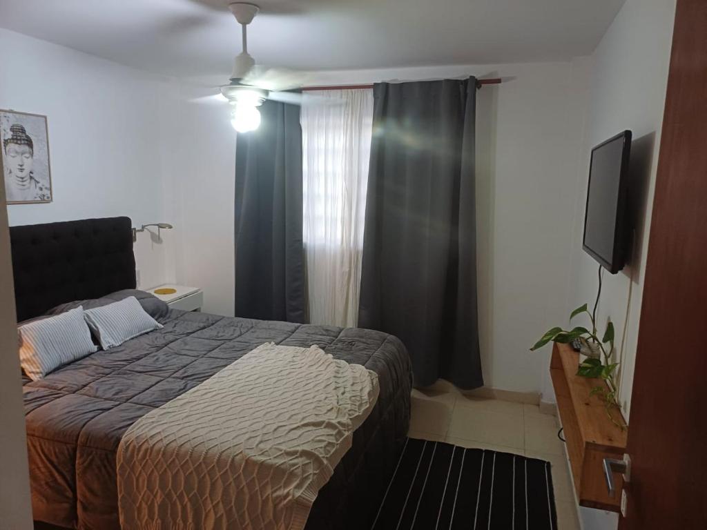 a bedroom with a bed and a window with a television at Depto Costa in San Bernardo
