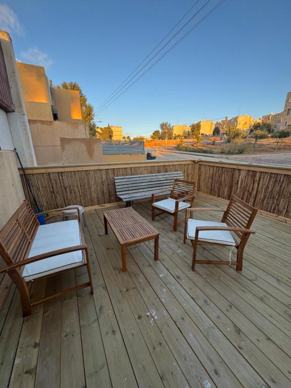 drei Holzbänke auf einer Holzterrasse in der Unterkunft אורנים in Mitzpe Ramon