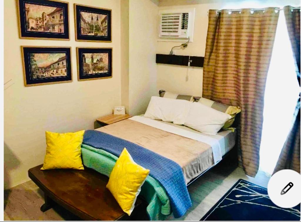ein Schlafzimmer mit einem Bett mit gelben und blauen Kissen in der Unterkunft Vintage Modern Studio Condo Unit with Balcony in Bacolod City