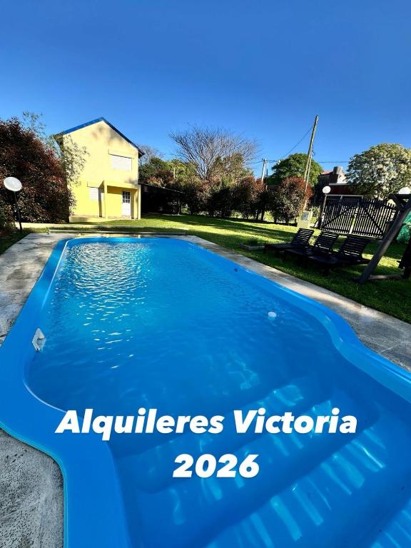 a blue swimming pool with a house in the background at Benjamín Relax in Victoria