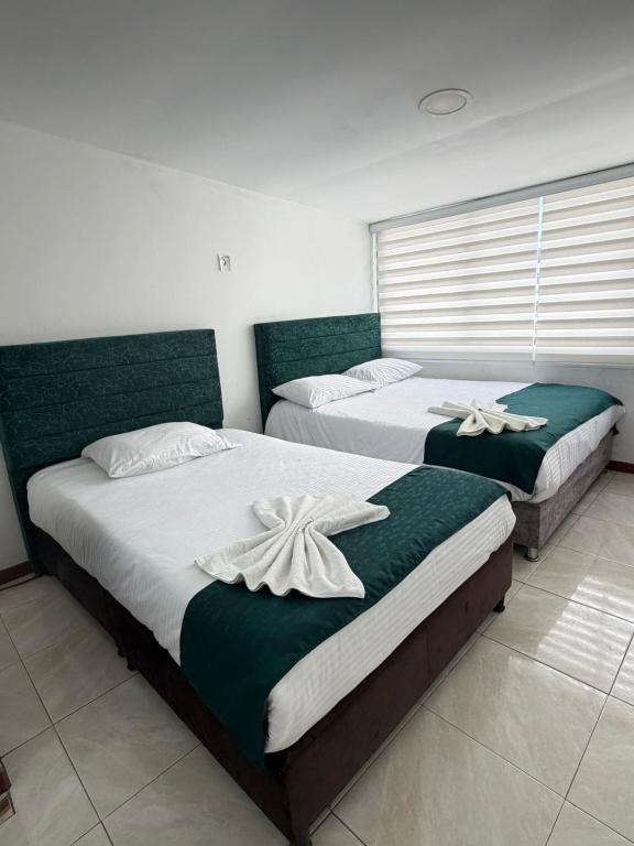 two beds in a bedroom with green and white at Hotel Hierbabuena y Restaurante in Pasto