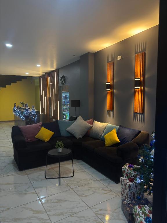 a living room with a black couch with yellow pillows at Hotel Mochomos Huajuapan in Huajuapan de León