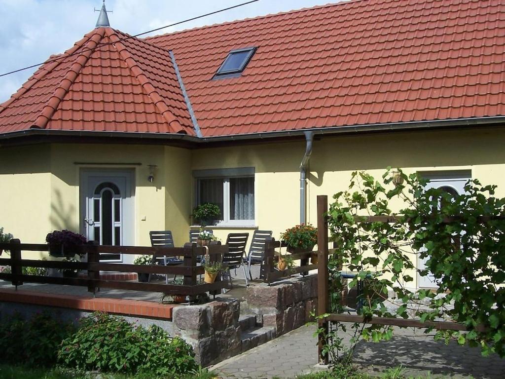 ein Haus mit einem roten Dach mit Stühlen und einem Zaun in der Unterkunft Holiday apartment in Parlow with parking in Parlow-Glambeck