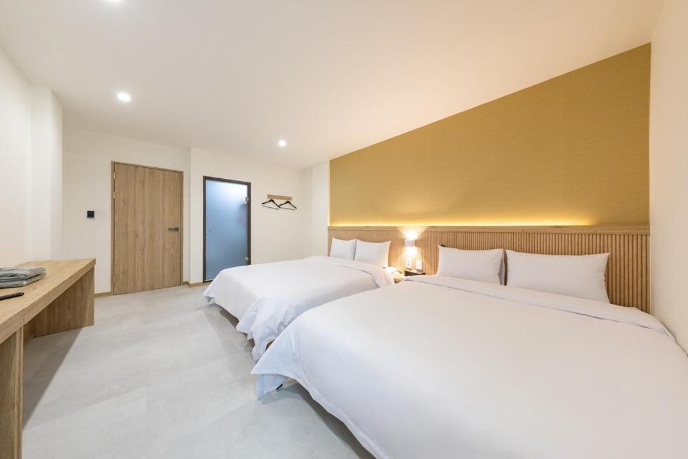 a bedroom with two beds and a desk at Agabara Gangneung in Gangneung