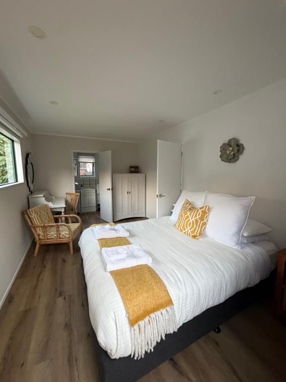 een slaapkamer met een groot wit bed met oranje en witte kussens bij The Hut in Russell