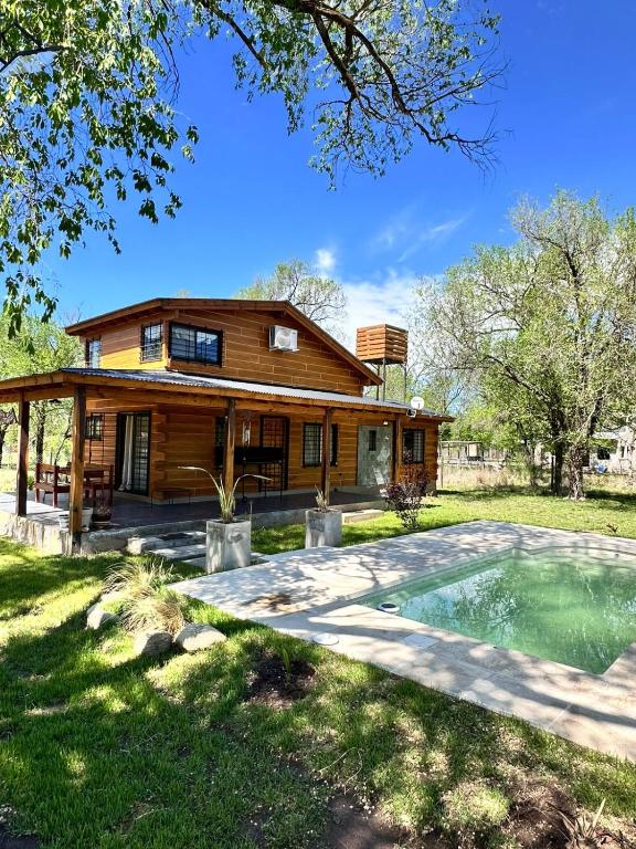 a log house with a pool in front of it at Cabaña para 6 personas en Calamuchita - Córdoba - "La Concepción" in Embalse Rio Tercero