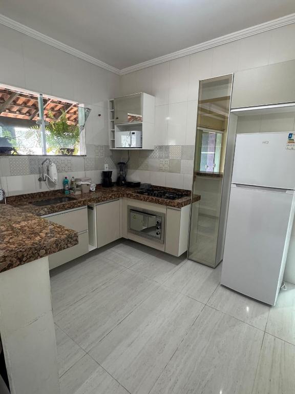 eine Küche mit weißen Geräten und einem weißen Kühlschrank in der Unterkunft Casa da lagoa in São Pedro da Aldeia