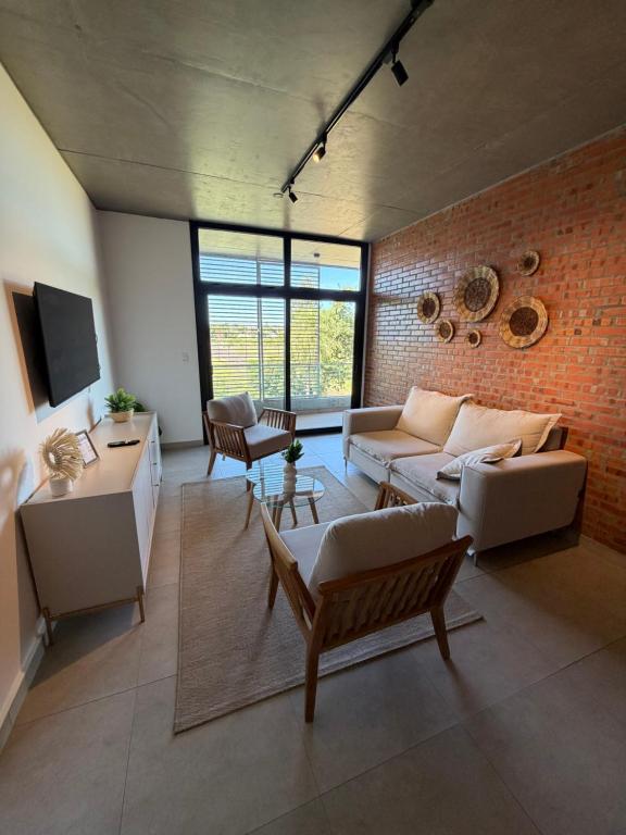 a living room with a couch and a brick wall at Bello departamento en Encarnación de 2 Habitaciones con Parking! in Encarnación
