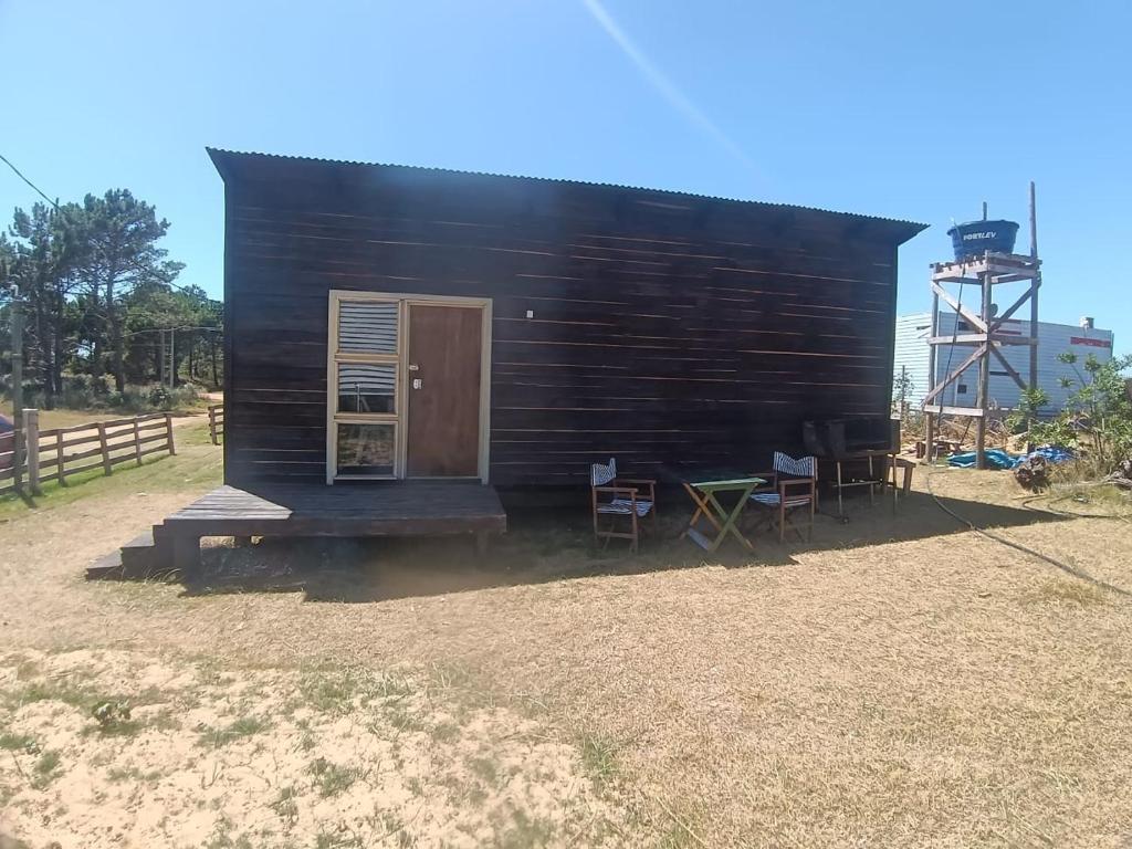 eine kleine Blockhütte mit Stühlen und einer Tür in der Unterkunft La viuda del diablo cabañas in Punta Del Diablo