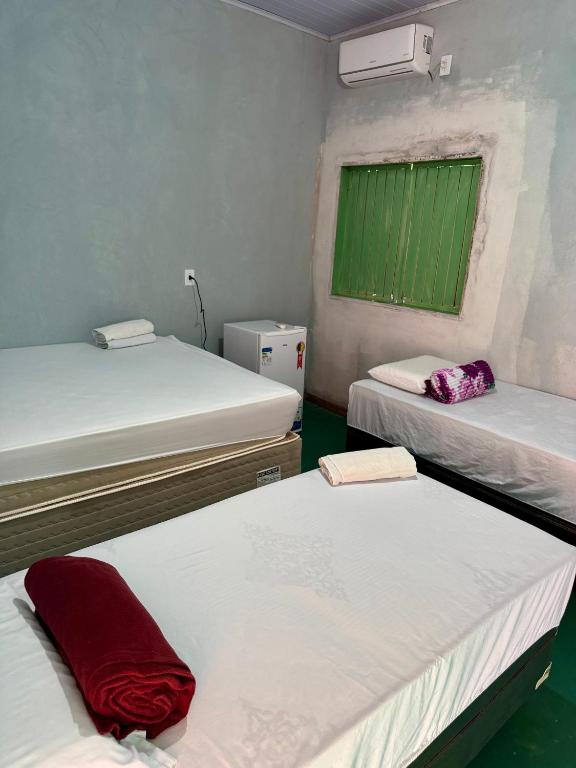 a room with two beds and a green window at Pousada e Camping São José in Manhã