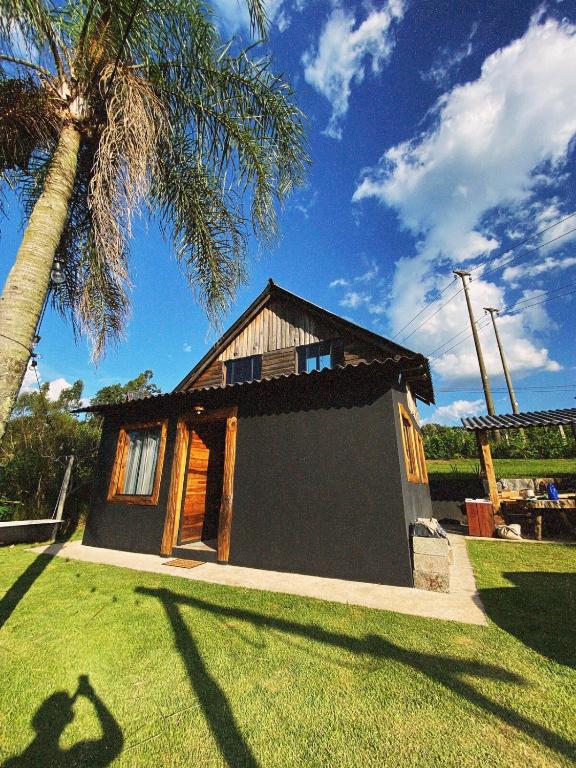 a small house in a yard with a palm tree at Cabana Rústica em Piedade in Piedade