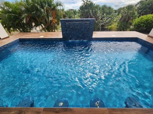 ein großer blauer Pool mit einem Stuhl darin in der Unterkunft Sunset Oasis Waterfront in Maya Beach