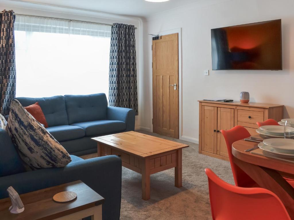 ein Wohnzimmer mit einem blauen Sofa und einem Tisch in der Unterkunft Ransdale Cottage in Bridlington