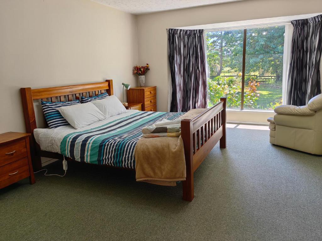 a bedroom with a bed and a window and a chair at Cozy 1 安逸舒适小屋 in Christchurch