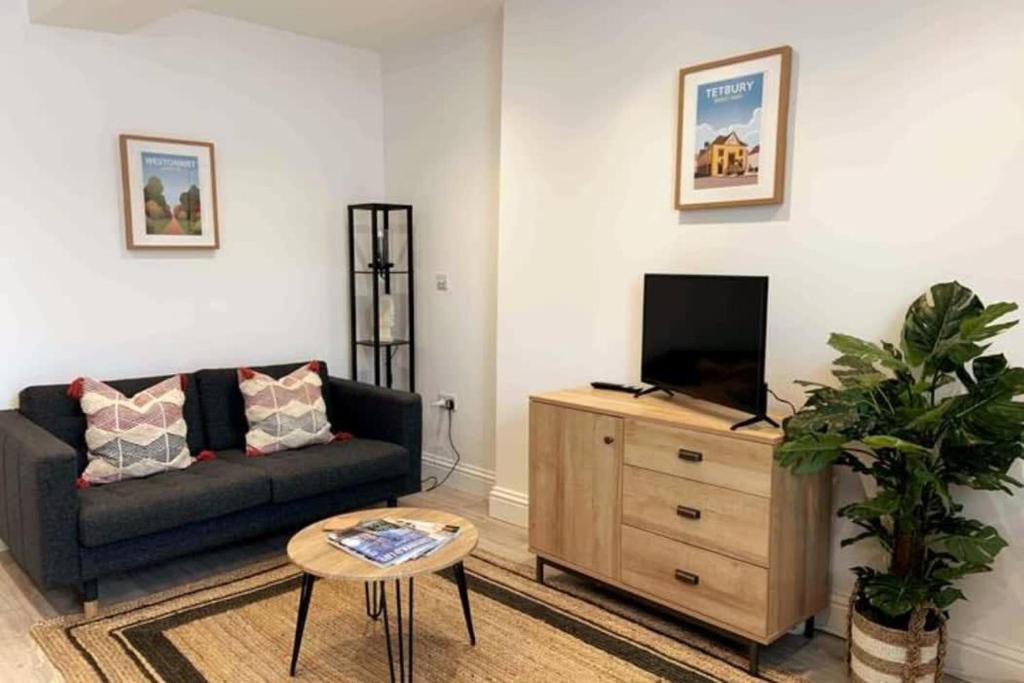 a living room with a couch and a tv on a wooden dresser at New contemporary apartment in centre of Tetbury in Tetbury