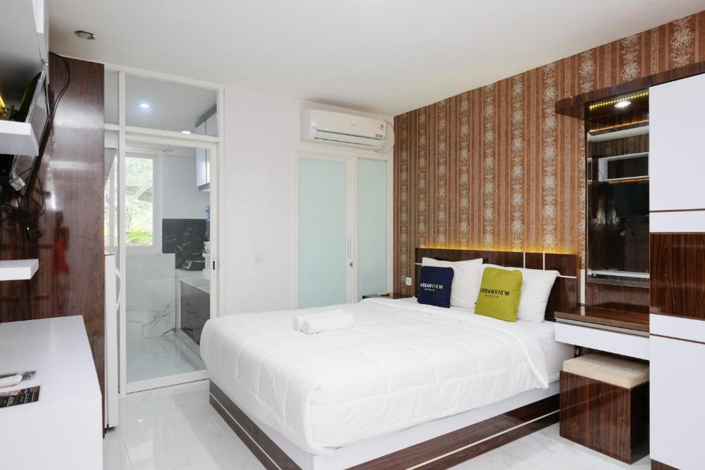 a bedroom with a white bed and a shower at Urbanview Hotel DHelomi Homestay near UPN Veteran in Kalasan