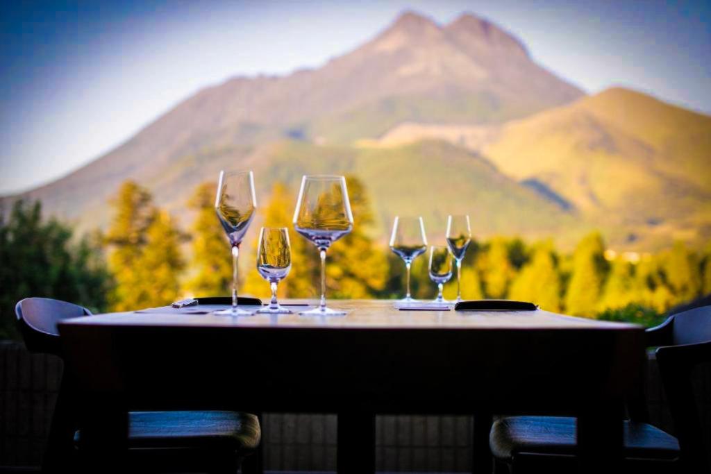 quattro bicchieri di vino su un tavolo con uno sfondo di montagne di Saigakukan a Yufu