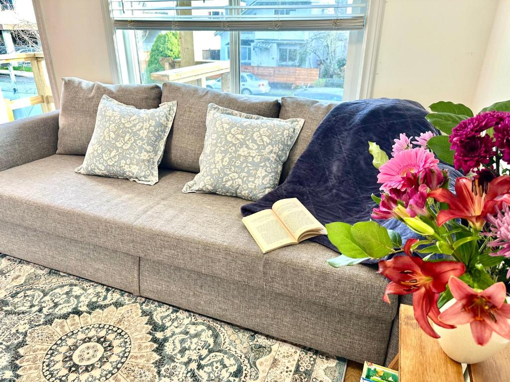 een bank met twee boeken en een vaas met bloemen bij Private Entire Guest Suite, 1 min to bus stops to Downtown and major attractions in Vancouver