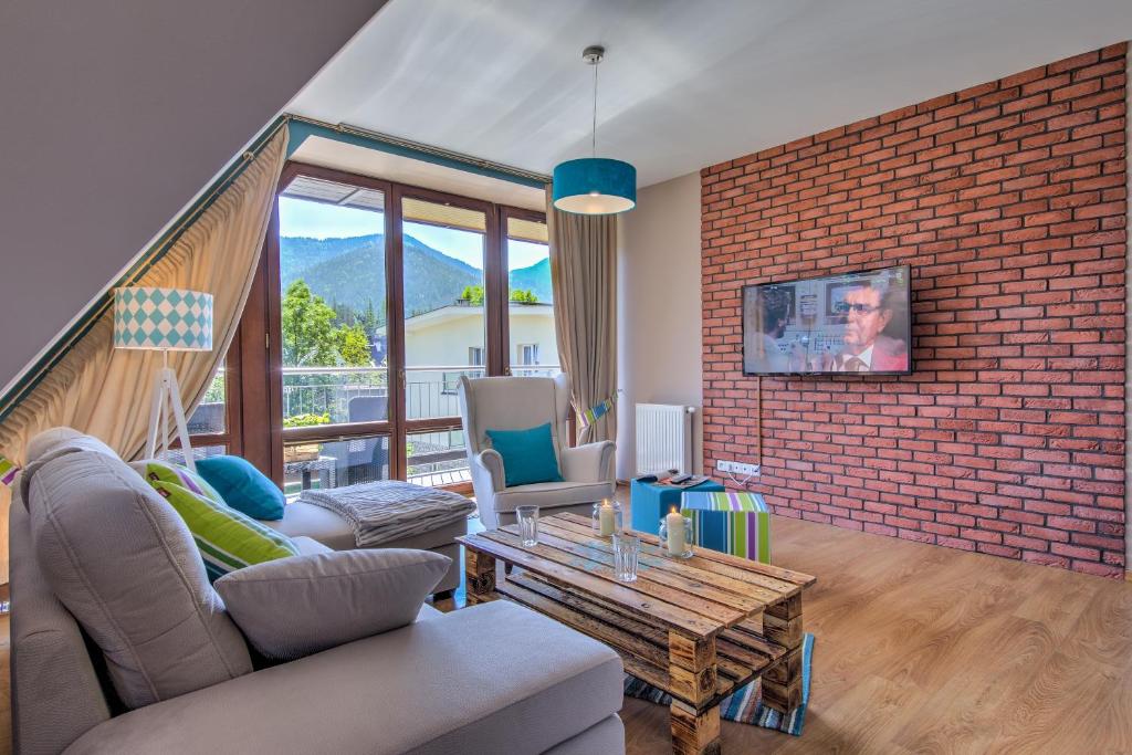 - un salon avec un canapé et un mur en briques dans l'établissement Apartamenty Oaza Deluxe Zakopane, à Zakopane