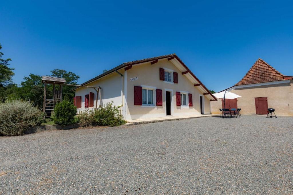 a white house with red shutters on a driveway at Bachale in Lamothe