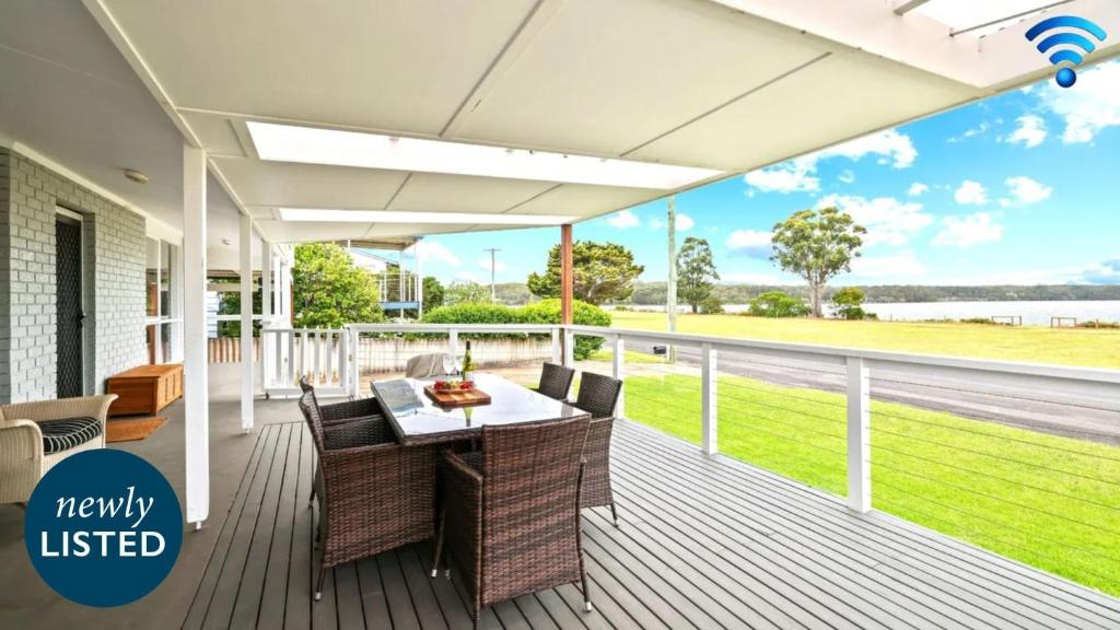 a deck with a table and chairs on a house at Riverside Retreat in Greenwell Point