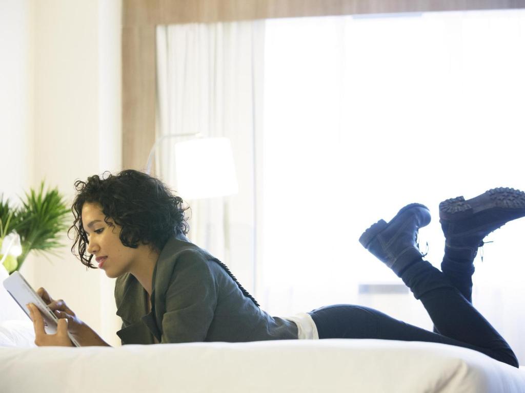 a woman laying on a couch reading a book at Novotel RJ Porto Atlantico in Rio de Janeiro