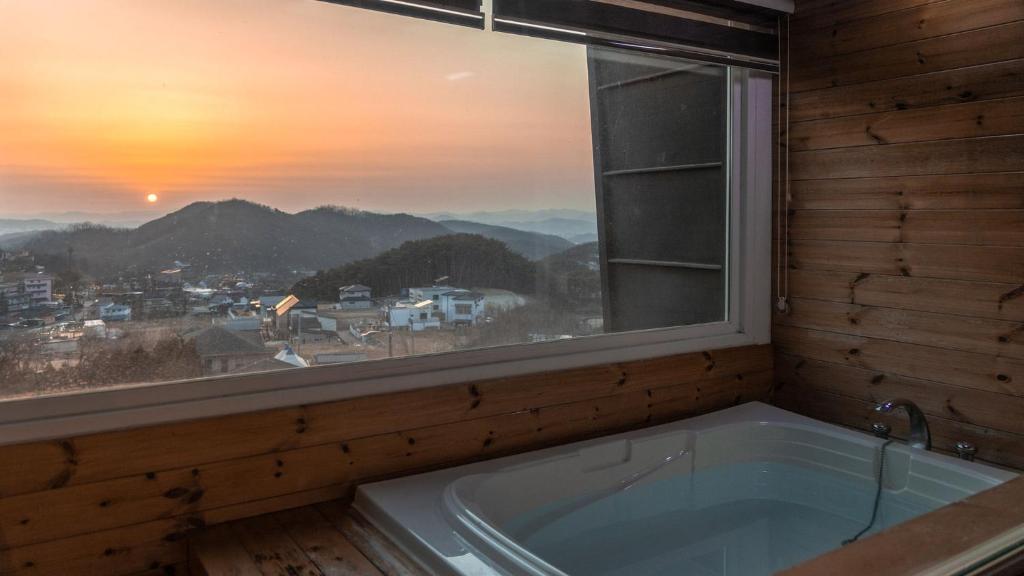 a bath tub in a room with a window at Wonju Quirinale Pension in Wonju