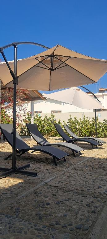 a row of chairs under an umbrella on the beach at Residencia playa Punta Veleros in Los Órganos